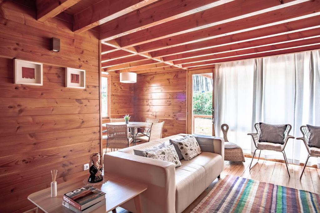 a living room with a white couch and wooden walls at Bungalow B5 Ofir in Fão