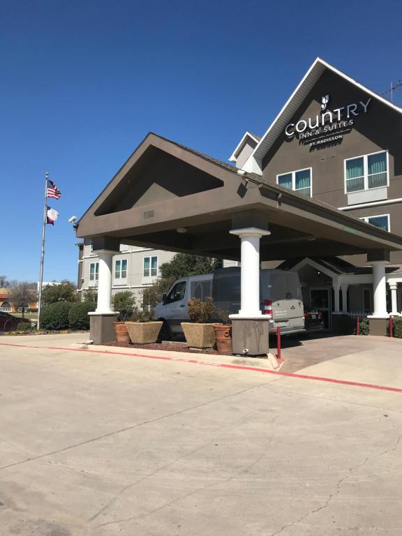 Country Inn & Suites by Radisson, Fort Worth, TX في فورت وورث: مبنى متوقف امامه سيارة