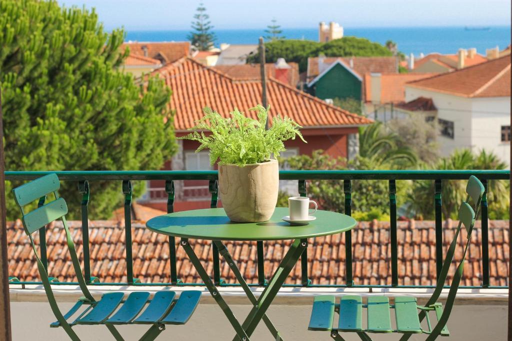 uma mesa com uma planta numa varanda com duas cadeiras em Your Place in Estoril em Estoril