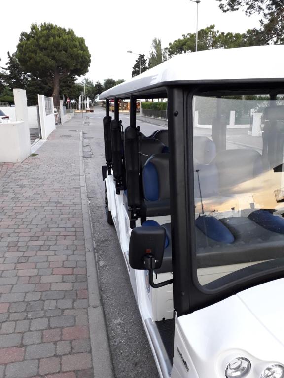 a white bus parked on the side of a street at Hotel Ambassador in Caorle