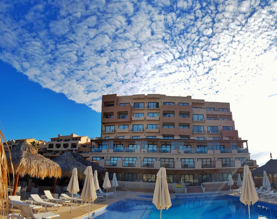 un hotel con sillas y sombrillas frente a un edificio en Marinaterra Hotel & Spa, en San Carlos