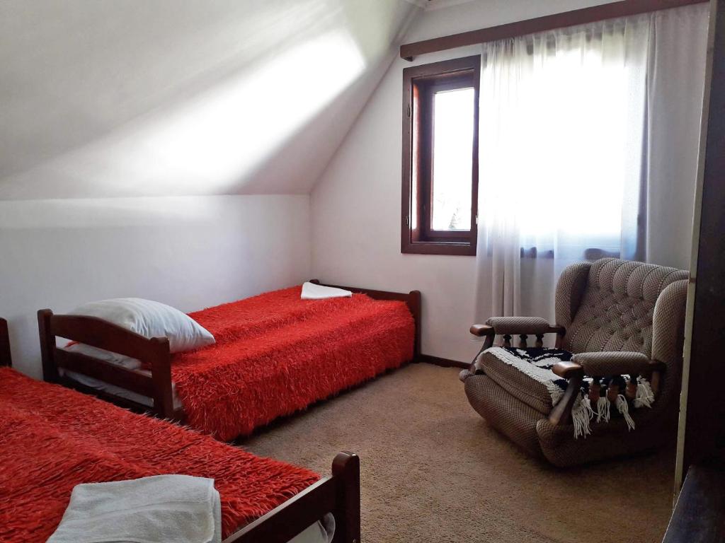 1 dormitorio con 2 camas, silla y ventana en Old Guest House 1964, en Žabljak