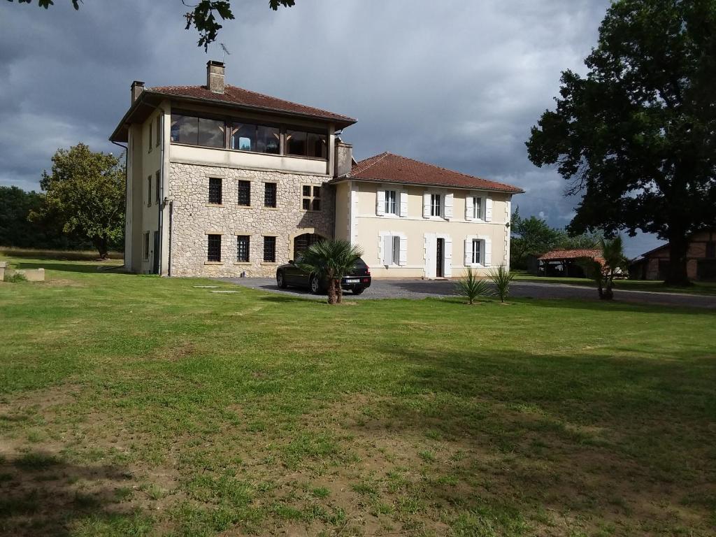 una gran casa blanca con un campo de hierba delante de ella en maison d'hôtes labastide en Villenave