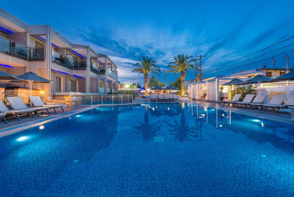 una piscina con sillas y un hotel en Dionysos Hotel & Suites en Hanioti