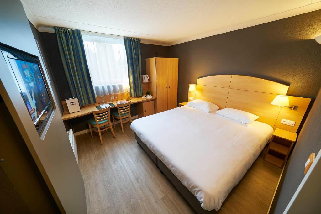 a hotel room with a bed and a desk and a table at DC Sleep & Go Brussels West in Brussels