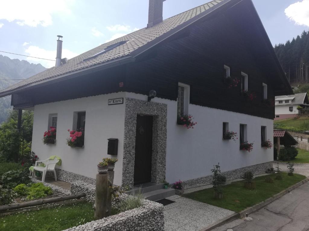 une maison blanche avec des fleurs sur les fenêtres dans l'établissement Apartma Arh, à Rateče