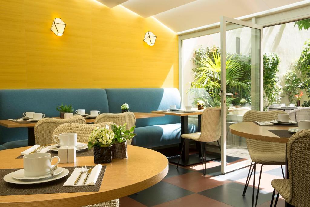 un ristorante con tavoli, sedie e finestre di Hôtel A La Villa des Artistes a Parigi