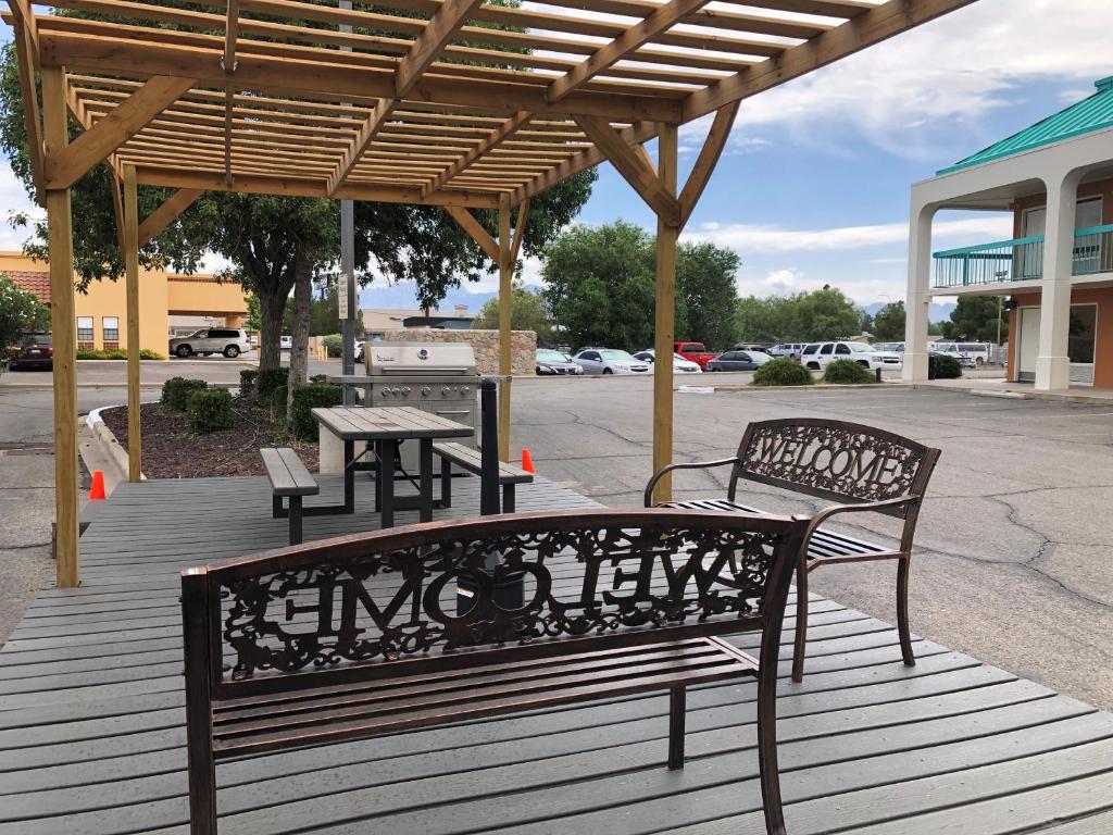 a wooden deck with two benches and a picnic table at Days Inn by Wyndham Las Cruces in Las Cruces