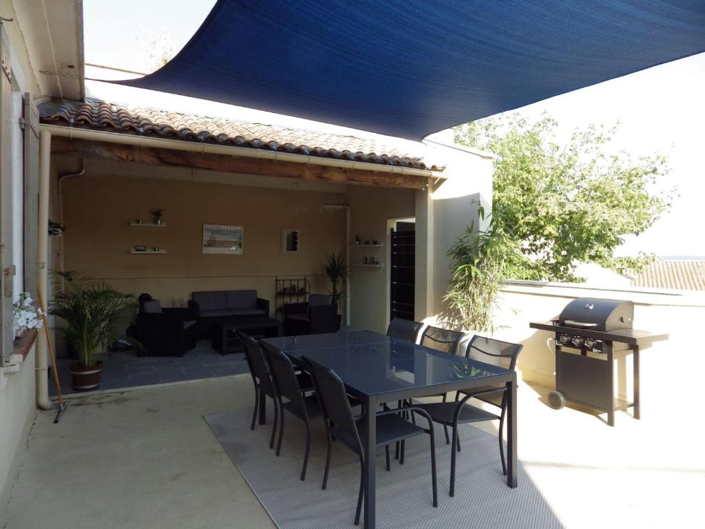 una mesa y sillas en un patio con una sombrilla azul en La Voile Bleue, en Châteauneuf-du-Pape