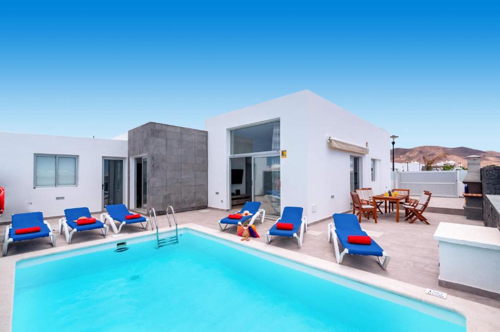 a swimming pool with blue chairs and a table at Villa Blue Horizon in Playa Blanca
