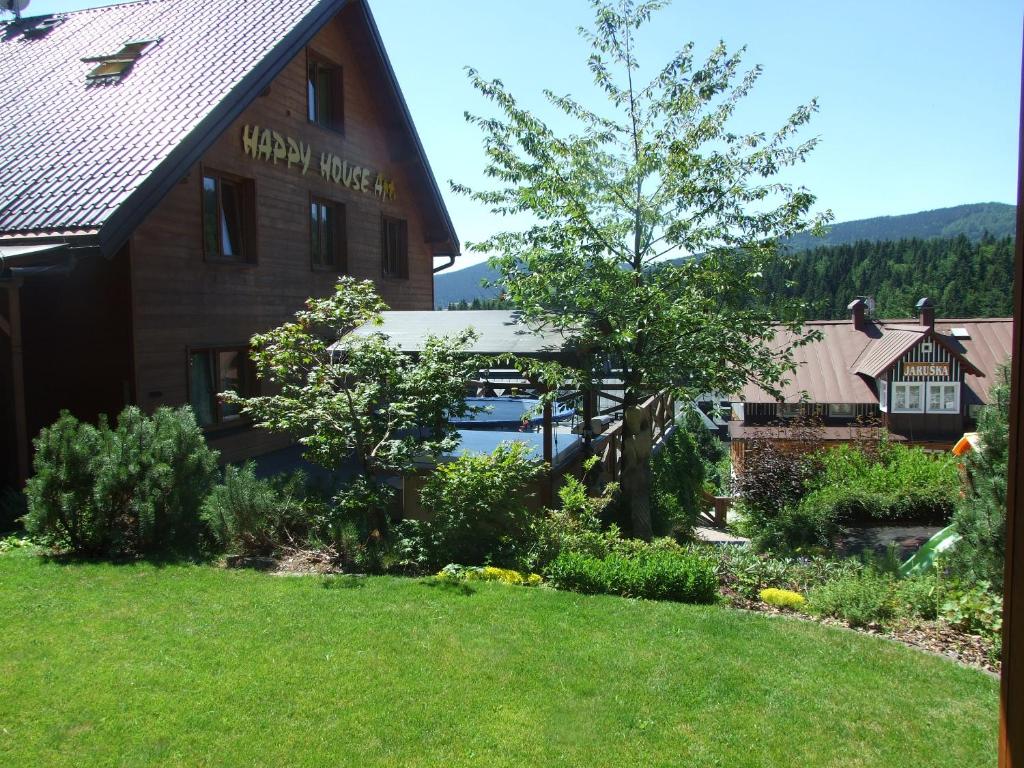 a house with a yard in front of a building at Happy House Apartments in Špindlerův Mlýn