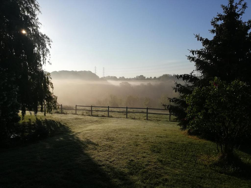 un campo con una valla y niebla en el fondo en La Vallée, en Saint-Martin-Saint-Firmin