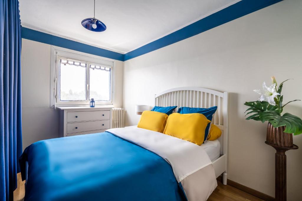 a blue and white bedroom with a bed with yellow pillows at Votre appartement à Poissy in Poissy