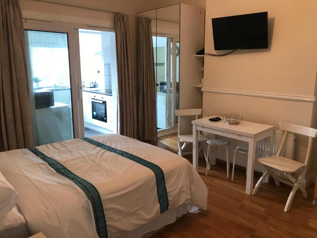 1 dormitorio con cama, mesa y TV en Gladstone Lodge Guest House, en Londres