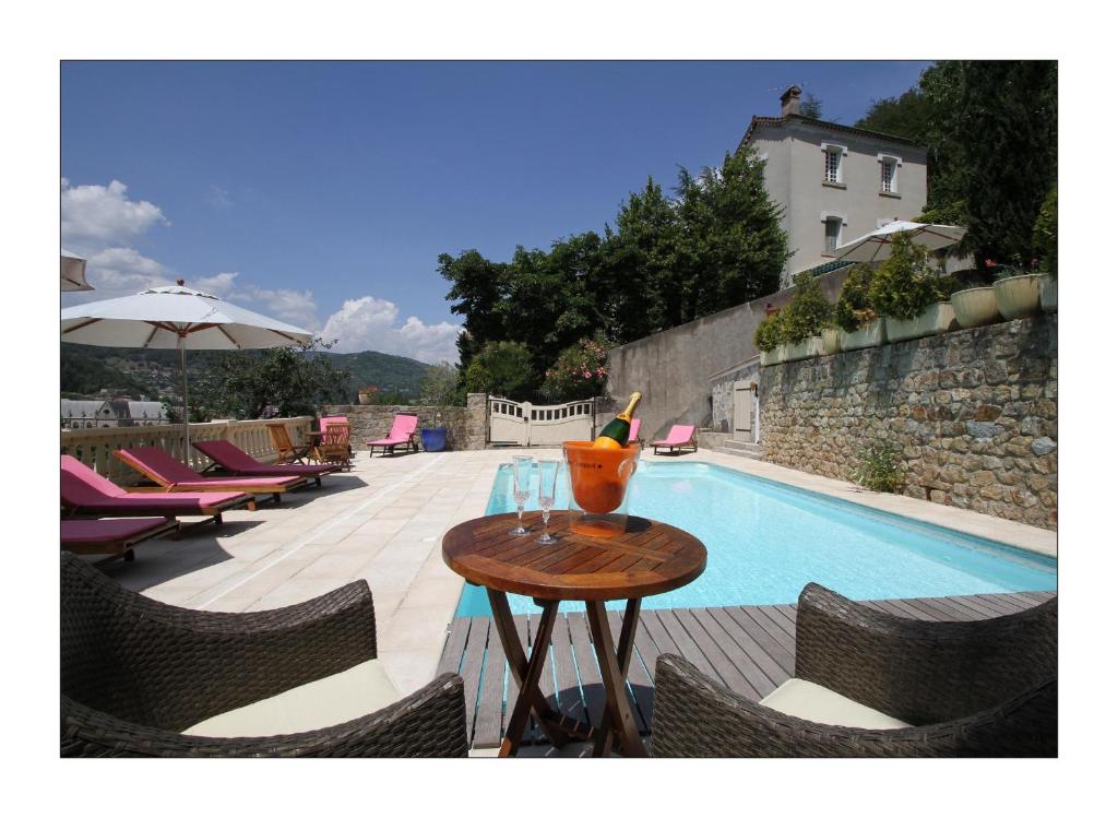 uma mesa com um vaso ao lado de uma piscina em Villa Aimée Luxury Apartments with Heated Pool em Vals-les-Bains