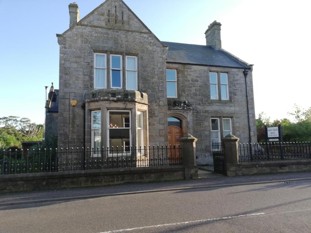 ein altes Steinhaus mit einem schwarzen Zaun in der Unterkunft Bank House in Thurso