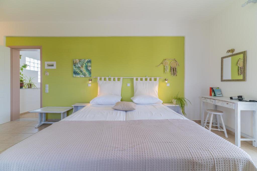 a bedroom with a white bed with a green wall at Kassiani Studios in Plakias