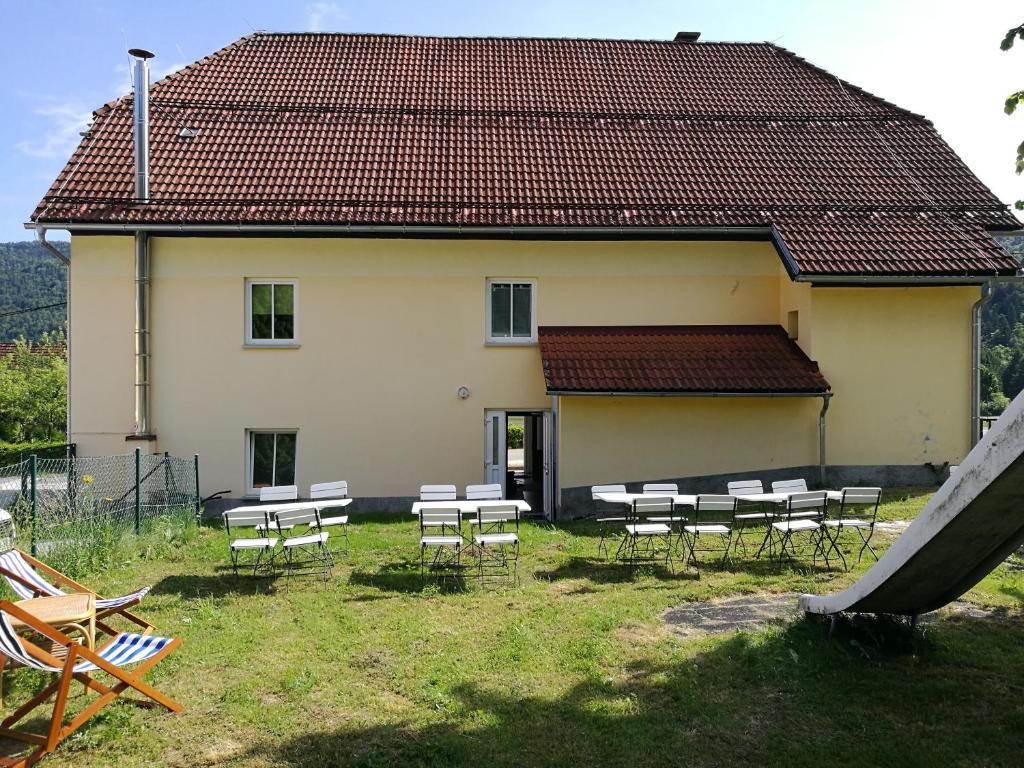 a building with tables and chairs in front of it at Počitniška hiša Ostrnica in Hrib-Loški Potok