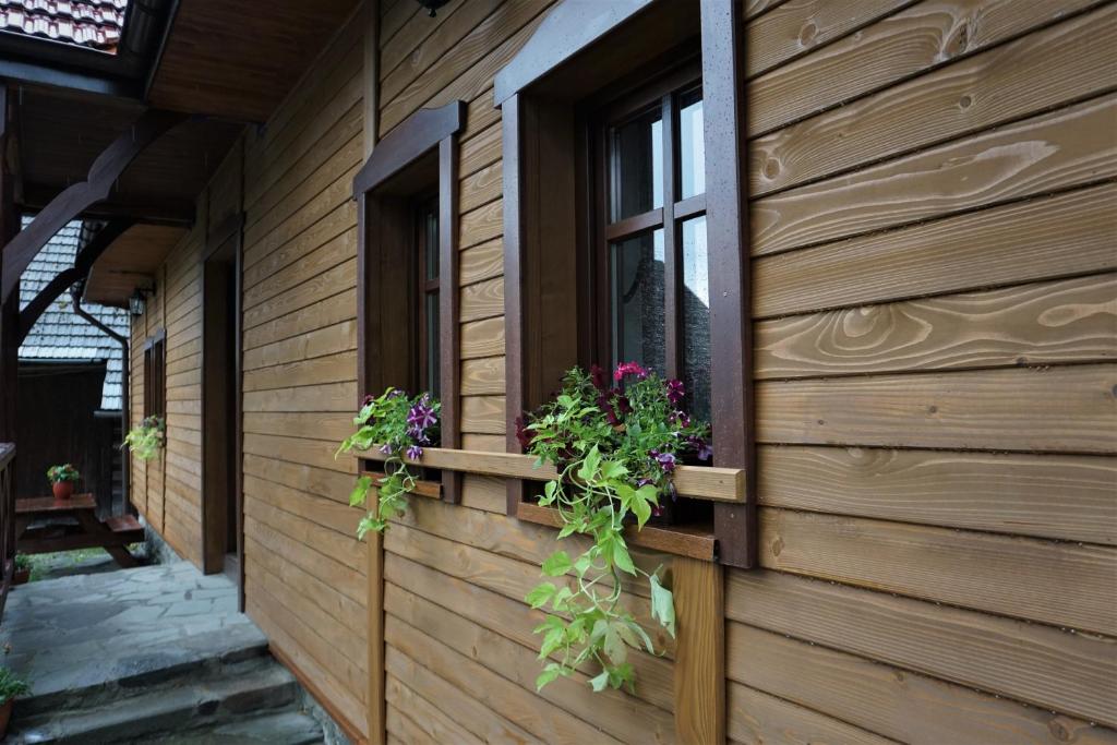 a building with two windows with flowers on it at Chata pod Mogielicą - klimatyczny dom na wyłączność z ogrodem i widokiem na góry in Słopnice