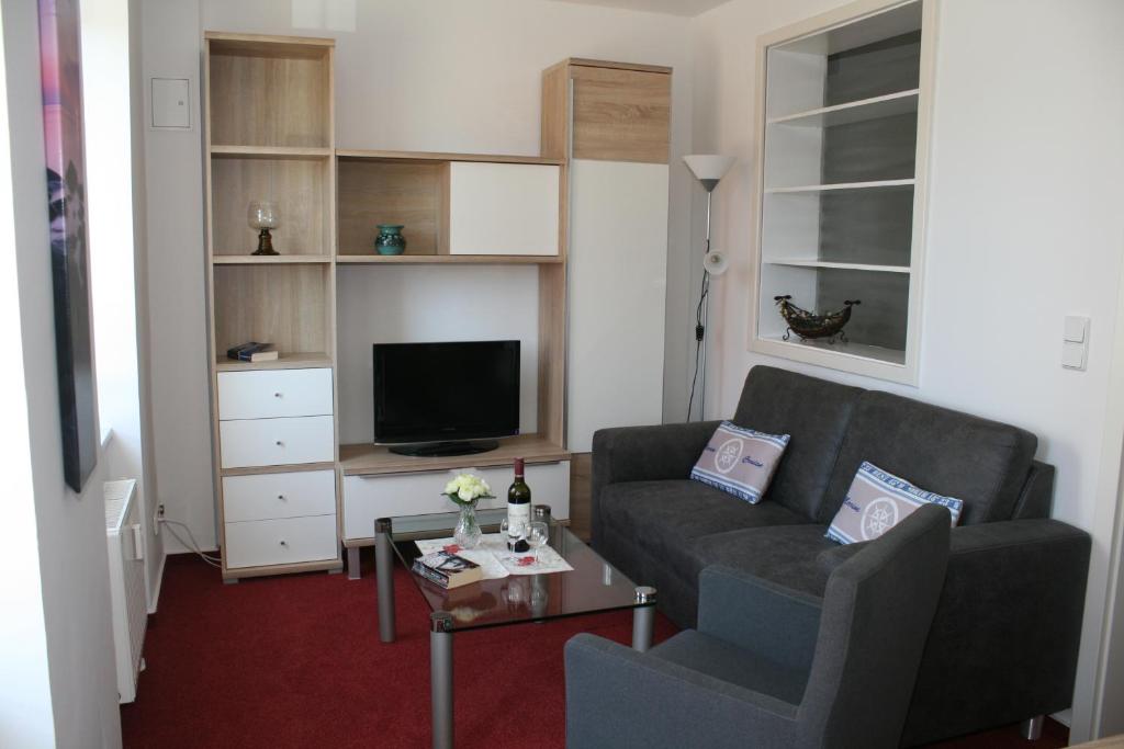 a living room with a couch and a tv at Garni Eden Hotels Villa Dora in Ahlbeck