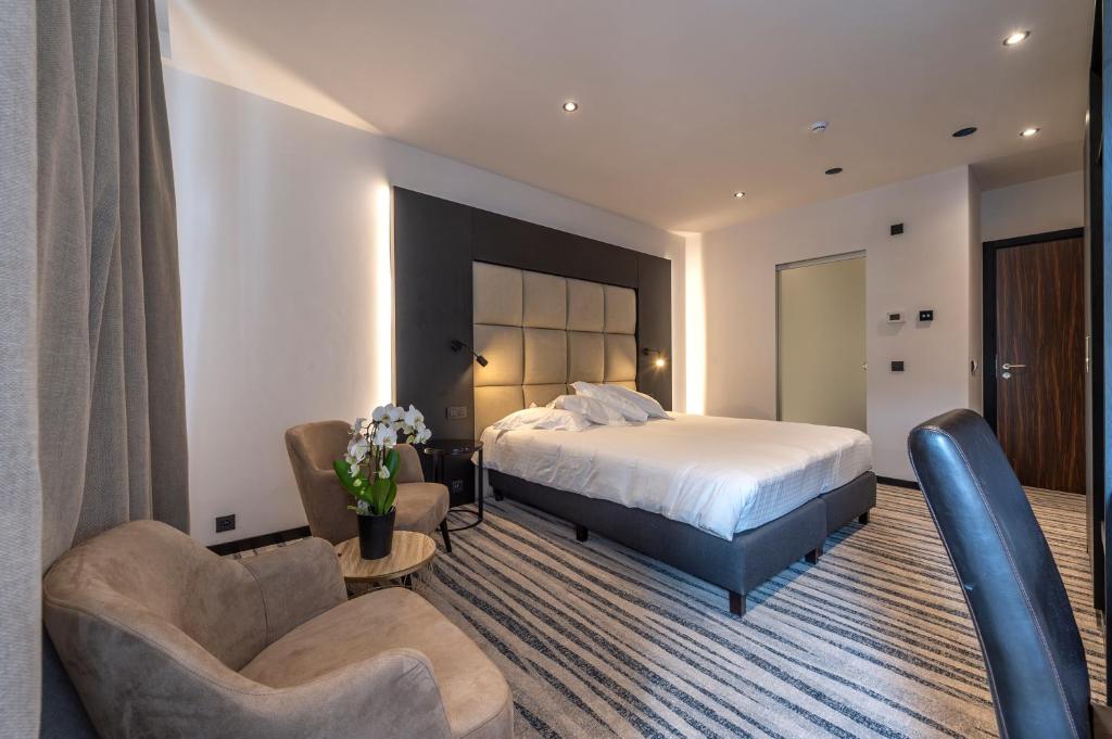 een hotelkamer met een bed en twee stoelen bij Hotel Monarc in Oostende