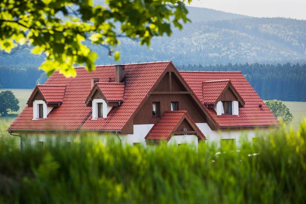 une maison avec des toits rouges dans un champ d'herbe dans l'établissement Przystanek Lasówka, à Lasowka