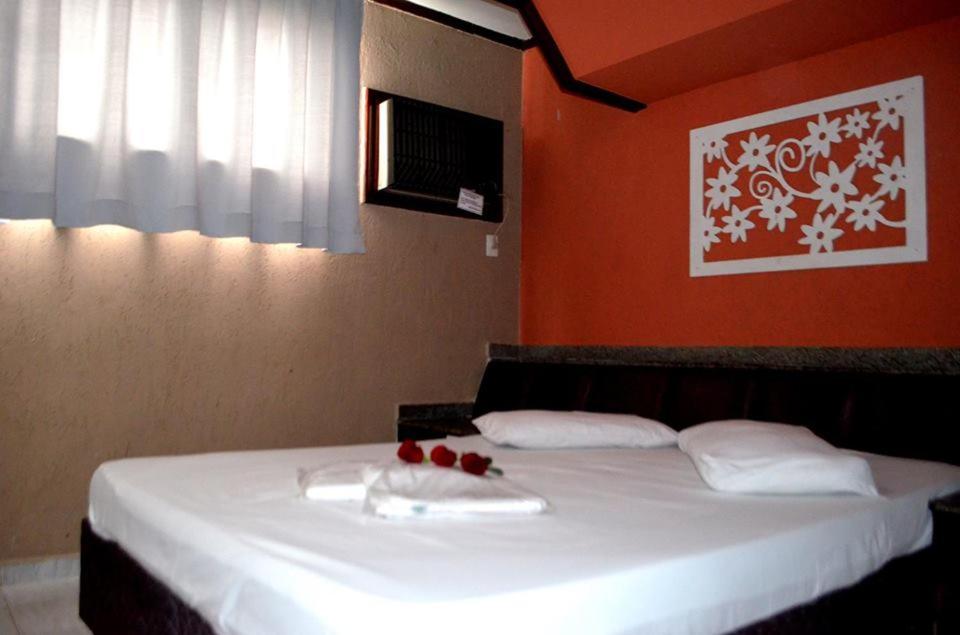 Motel & Hotel Free Love JF في جويز دي فورا: غرفة نوم بسرير بملاءات بيضاء وجدران حمراء