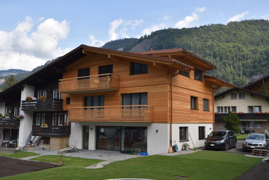 un gran edificio de madera con coches aparcados delante de él en Ferienwohnung Gemeindematte, en Meiringen