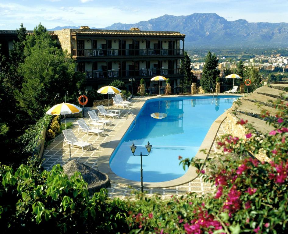 una gran piscina con sombrillas y sillas y un edificio en Parador de Tortosa en Tortosa