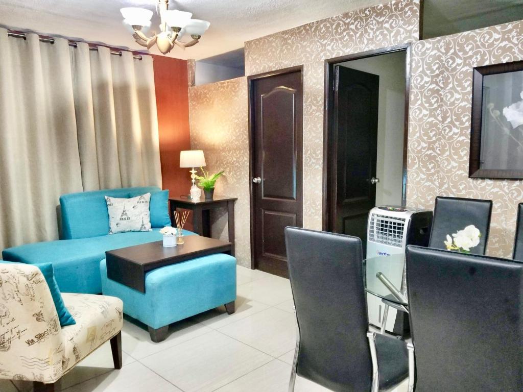 a living room with a blue couch and a table at Super Cute Hampton Suites in Imus