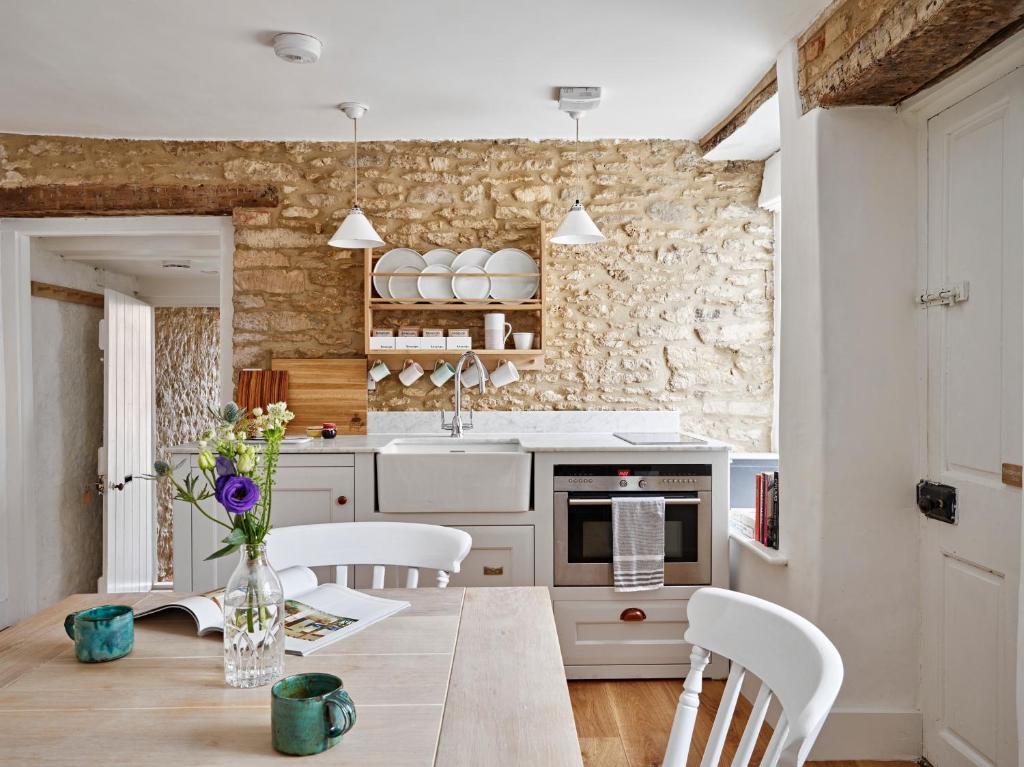 a kitchen with a wooden table and white cabinets at Artisan Cottage in Chippenham