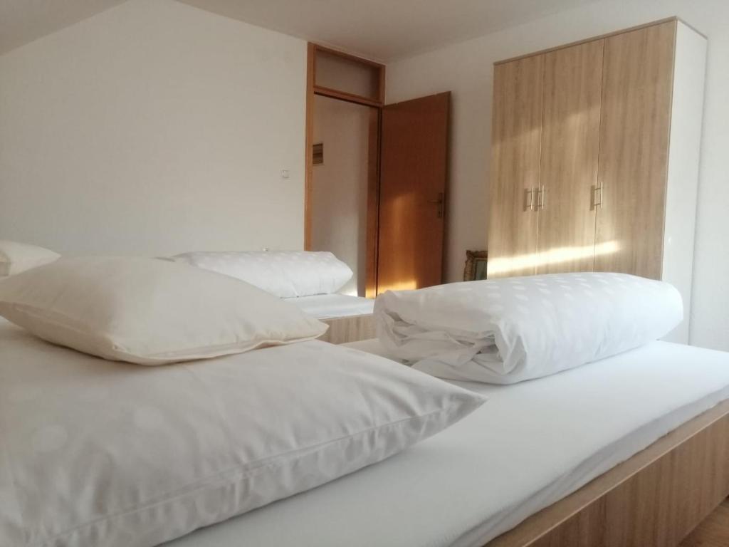 2 letti con lenzuola e cuscini bianchi in una stanza di Apartman AS a Livno