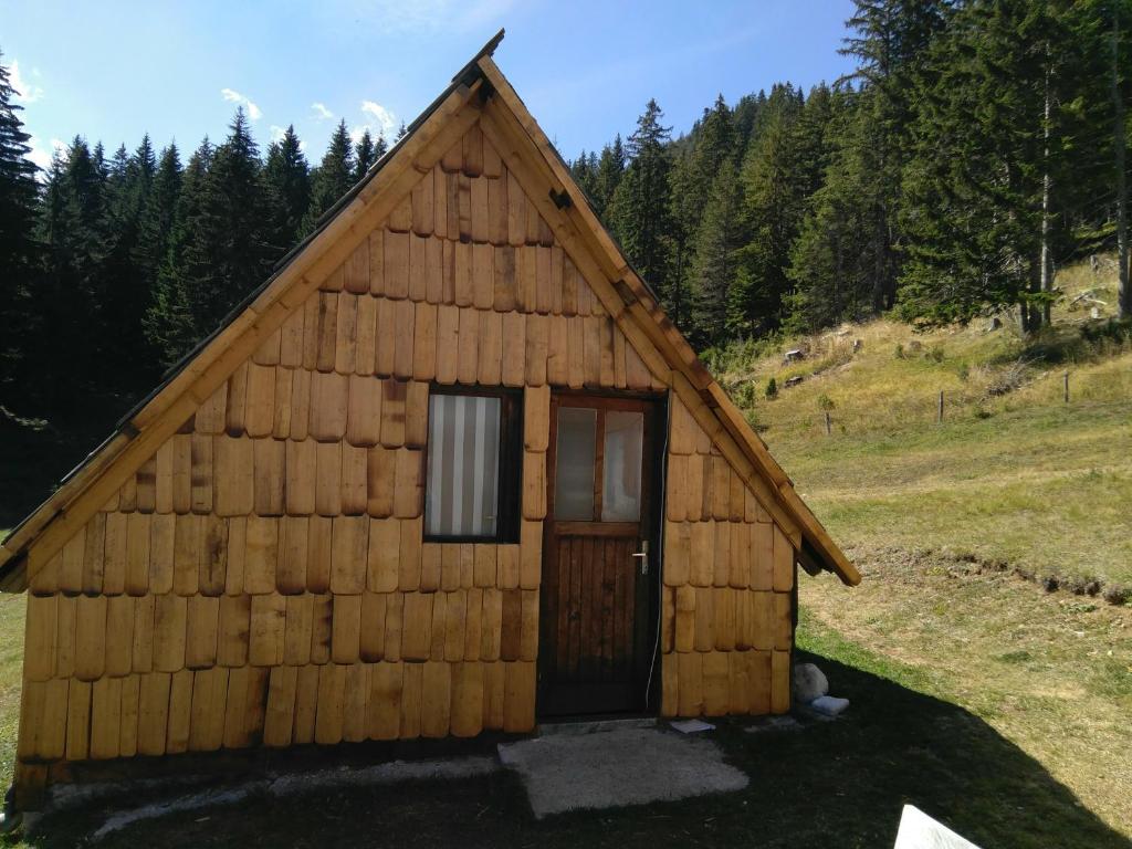 eine kleine Holzhütte mit einer Tür auf einem Feld in der Unterkunft Cottage Bosaca in Žabljak