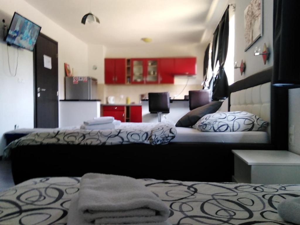 a bedroom with two beds and a kitchen with red cabinets at Guest House First Stop in Rakovica