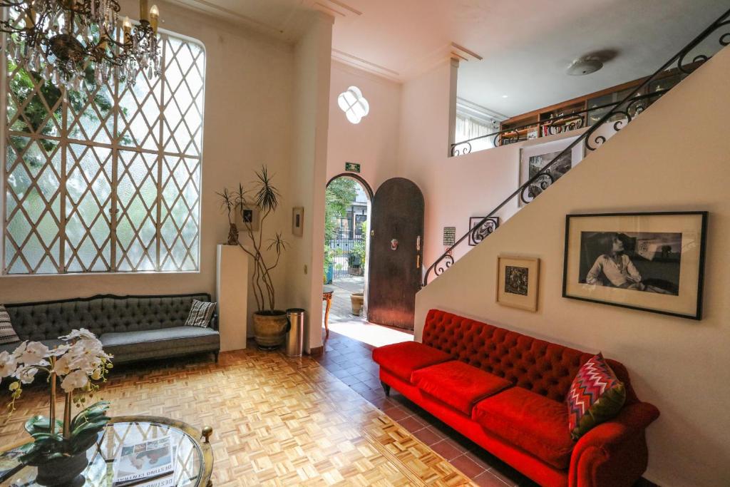 a living room with a red couch and a staircase at Casa Comtesse in Mexico City
