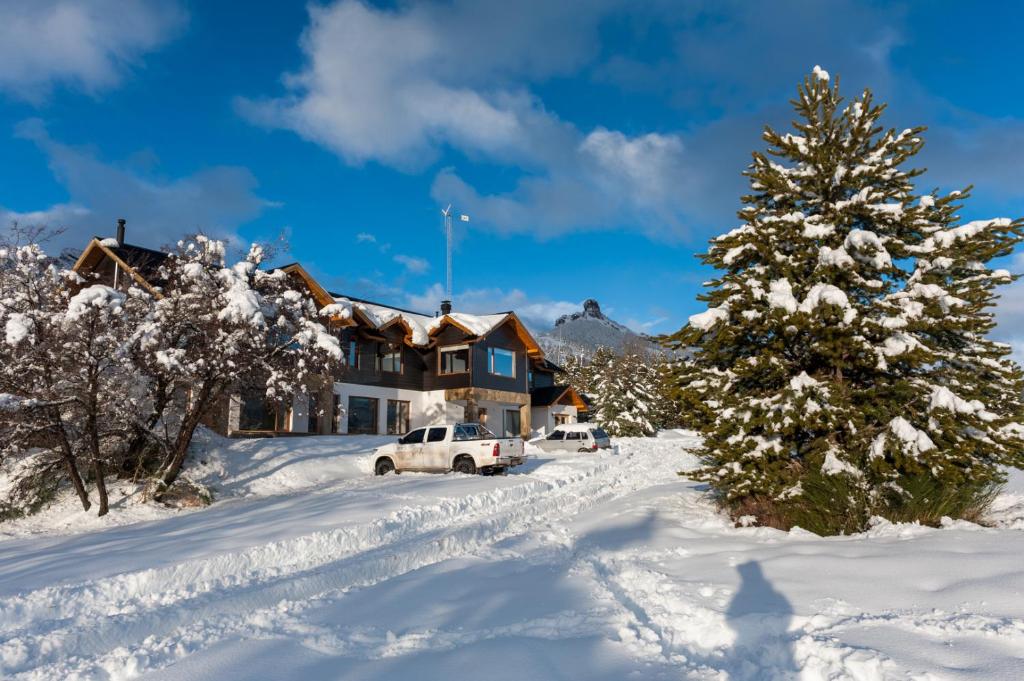 a house with a christmas tree in the snow at Cabañas & Apart Ruta 63 in Villa Meliquina