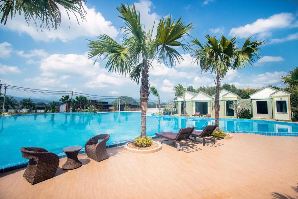 a large swimming pool with chairs and palm trees at Saichon Grand View in Ban Lam Rua Taek