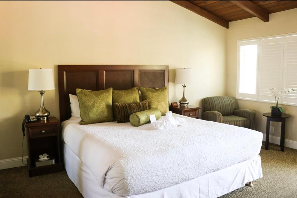 a bedroom with a large white bed and two chairs at Country Inn Motel in Palo Alto