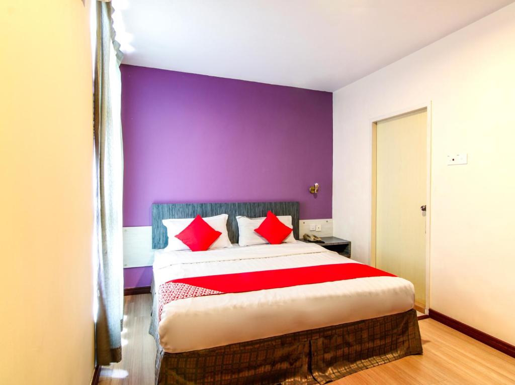 a bedroom with a large bed with a purple wall at Super OYO 43930 Hotel Esplanade in Sandakan