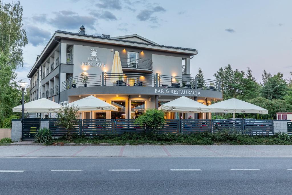 een groot gebouw met witte parasols ervoor bij Hotel Perłowy in Okuninka