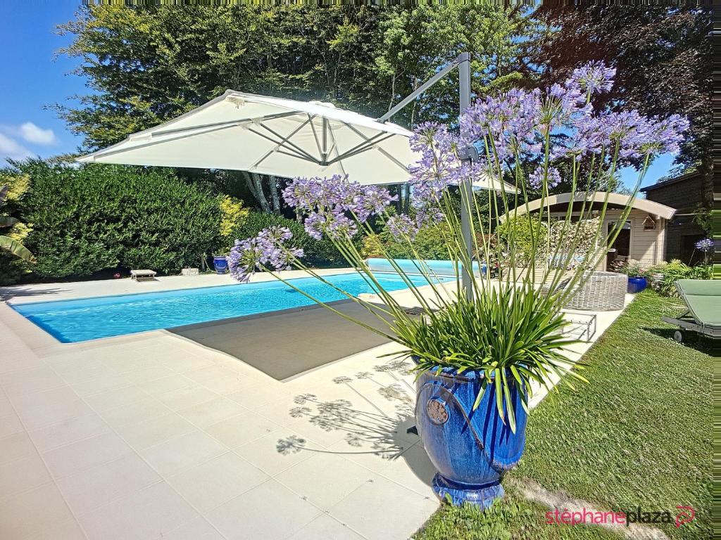 un jarrón azul con una sombrilla junto a una piscina en La maison de l'Odet, en Gouesnach