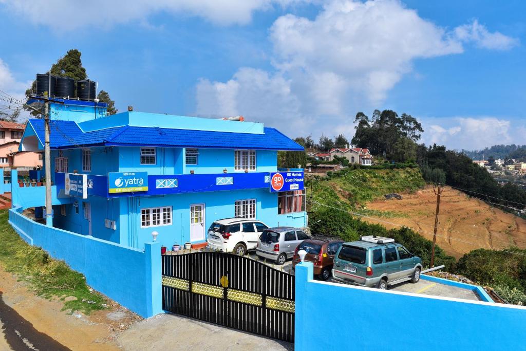 a blue building with cars parked in a parking lot at RK Holiday Home in Ooty