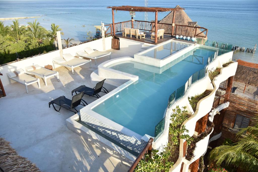 a swimming pool with chairs and the ocean in the background at Spirit Holbox in Holbox Island