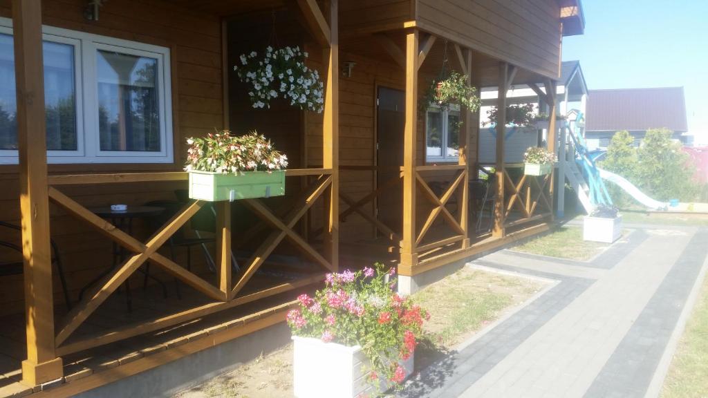 una casa con macetas de flores a un lado. en Domki Letniskowe TURKUS en Rewal