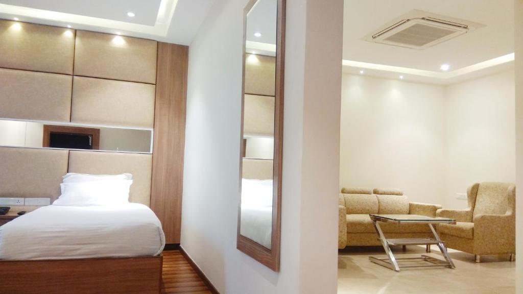 a bedroom with a bed and a chair and a mirror at Hotel Smart City Park Inn in Tada