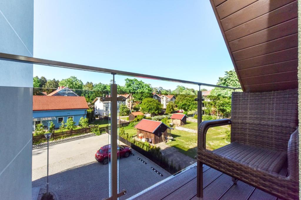 a balcony with a bench and a view of a street at Gėlių terasos - studija su balkonu in Juodkrantė