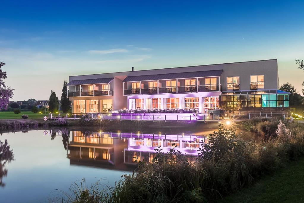 ein großes Gebäude neben einem Fluss in der Nacht in der Unterkunft Golfhotel & Restaurant Lindenhof in Bad Vilbel