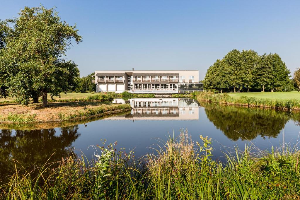 a large building next to a river with a building at Golfhotel & Restaurant Lindenhof in Bad Vilbel