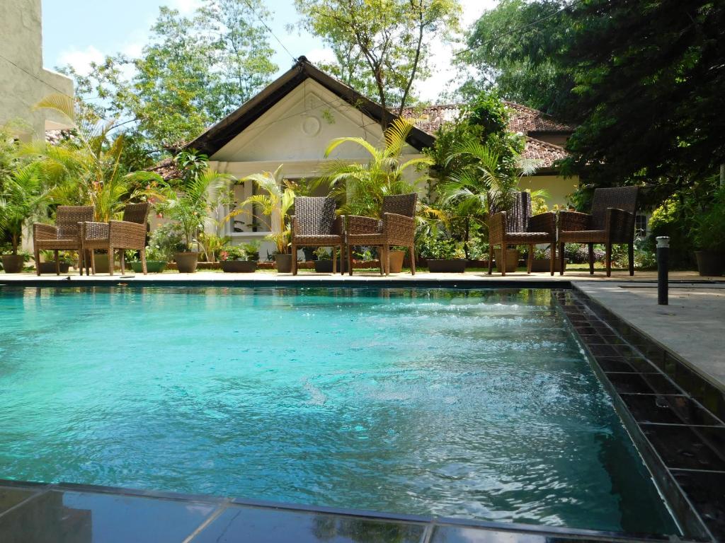 a swimming pool with chairs in front of a house at St Bridget's Country Bungalow in Kandy