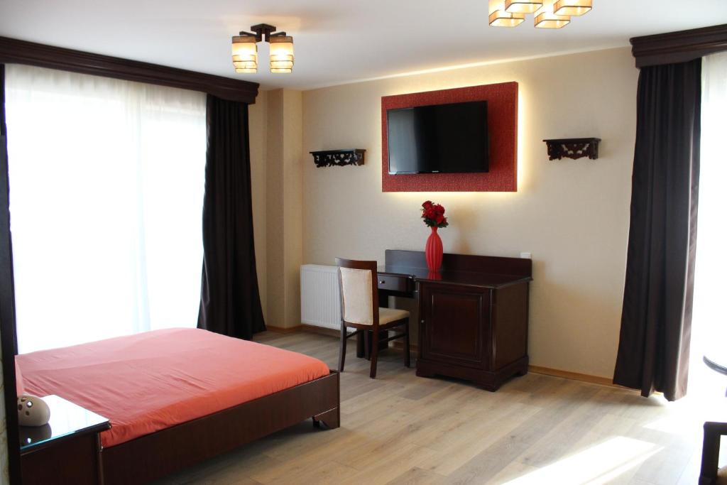 a bedroom with a bed and a desk with a television at Pensiunea Junior in Cluj-Napoca